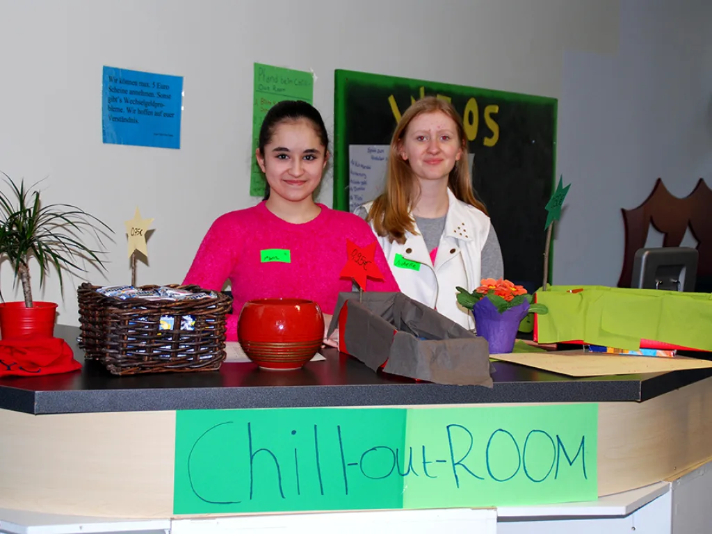 Zwei Jugendliche stehen an einem Stand mit dem Schild „Chillout-Room“.